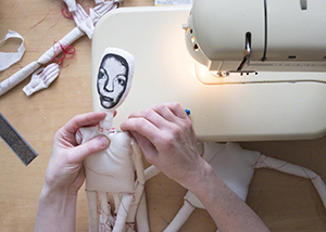 Closeup of Jody MacDonald sewing the neck of a figurative sculpture